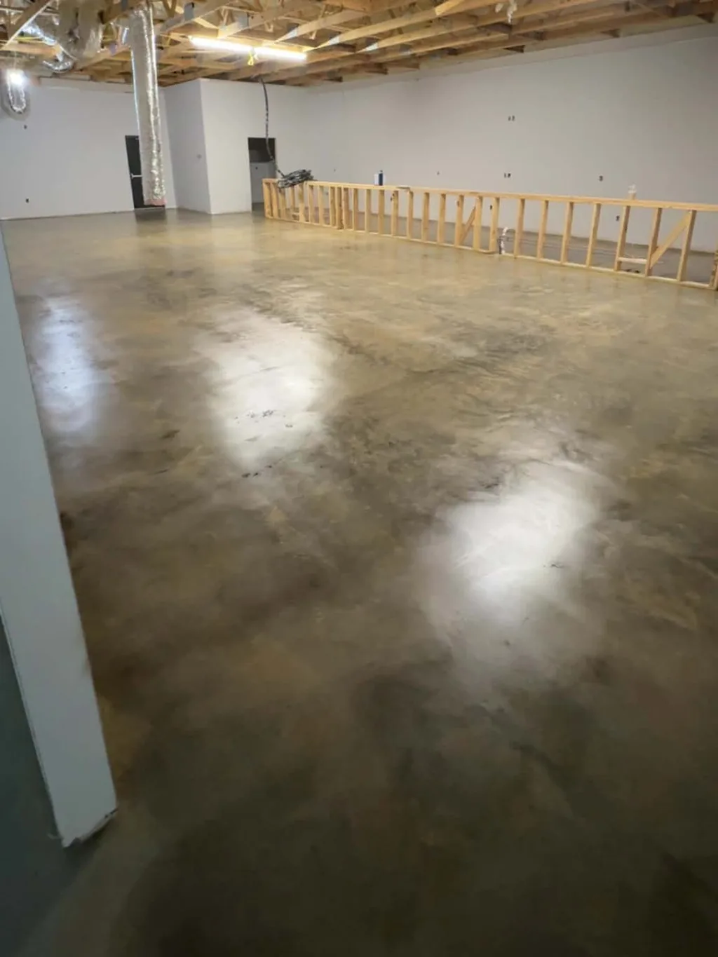 Large open commercial space in Mississippi with a stained and sealed concrete floor, walls framed and roof trusses exposed