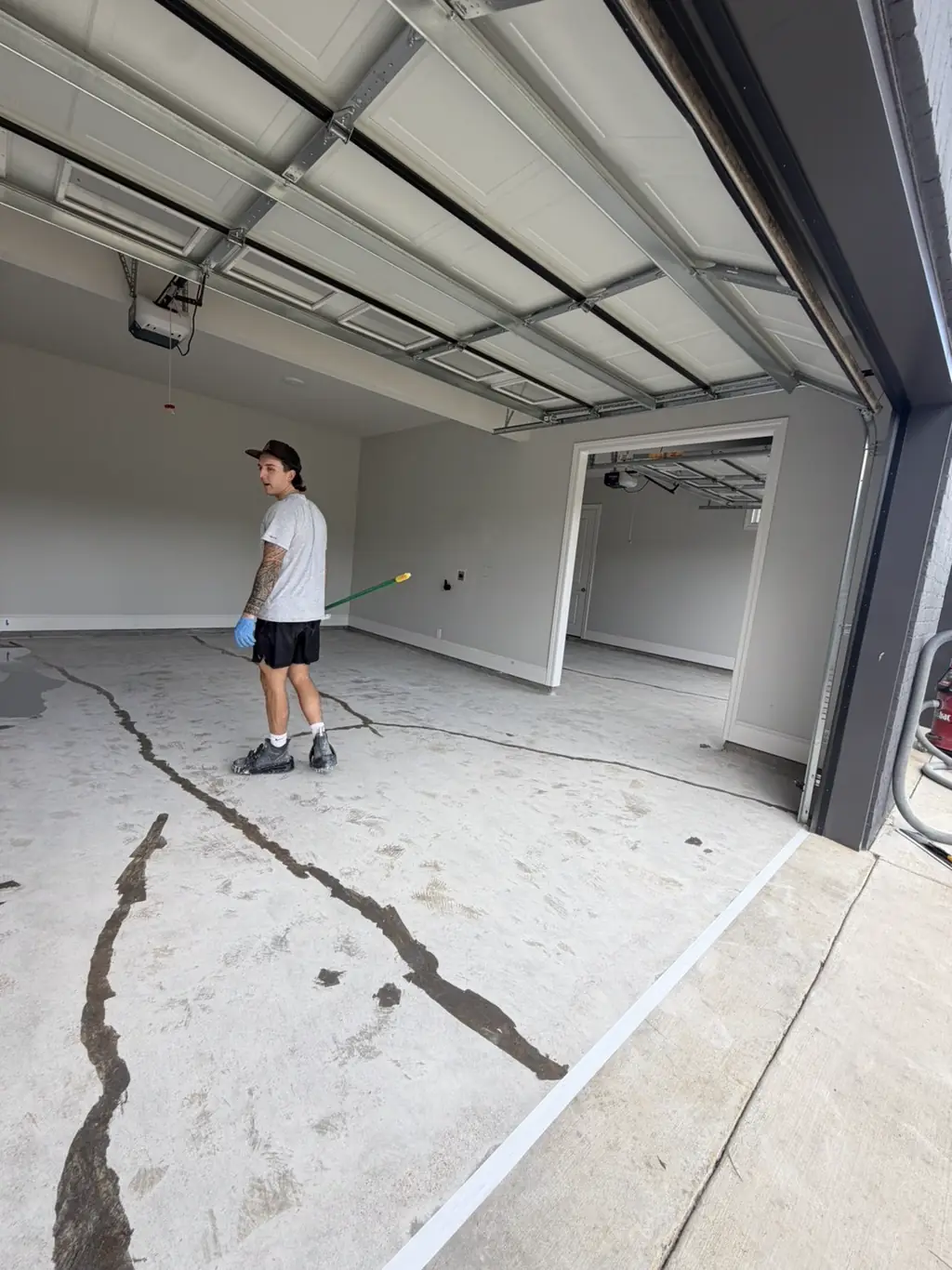 Cracked concrete garage slab being prepped before an epoxy coating goes down