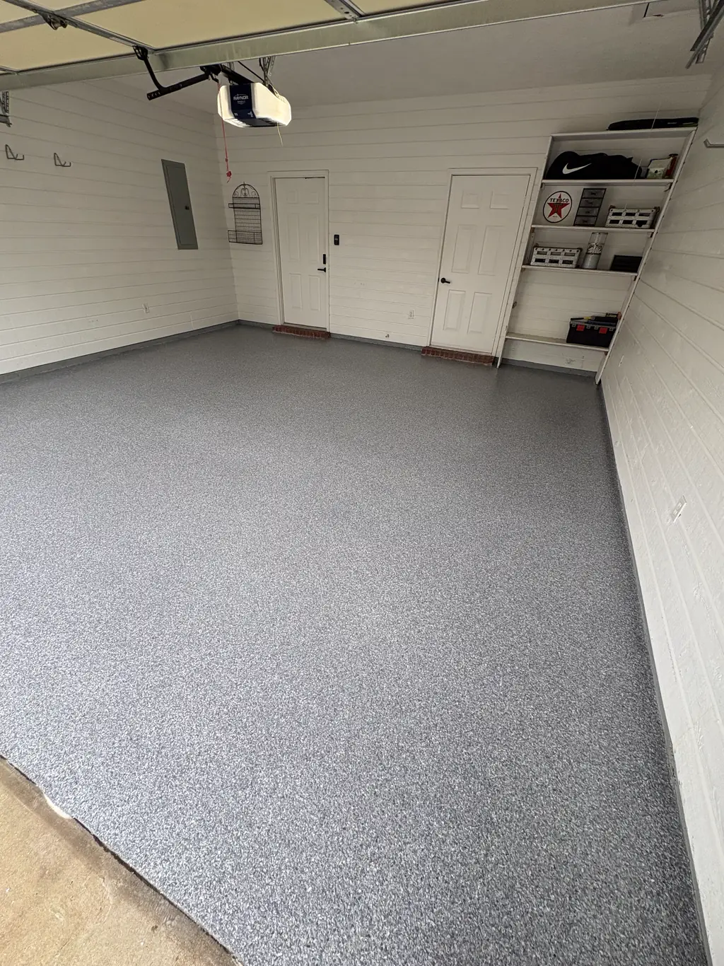 Clean finished garage with a light gray flake floor and storage shelving