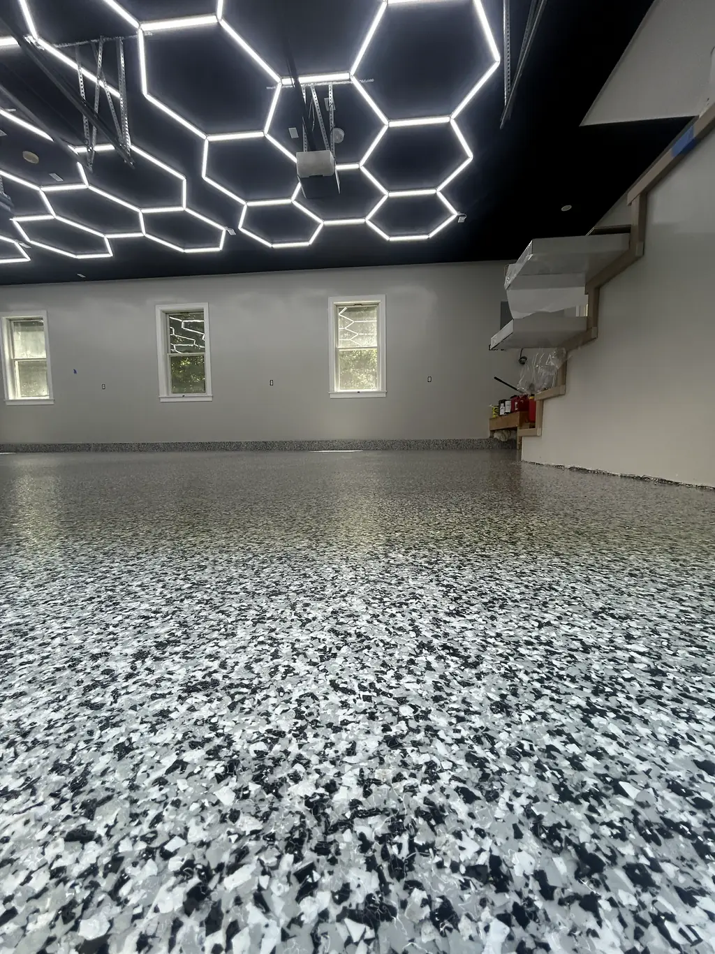 Garage with a black and white flake epoxy floor under hexagon LED shop lighting