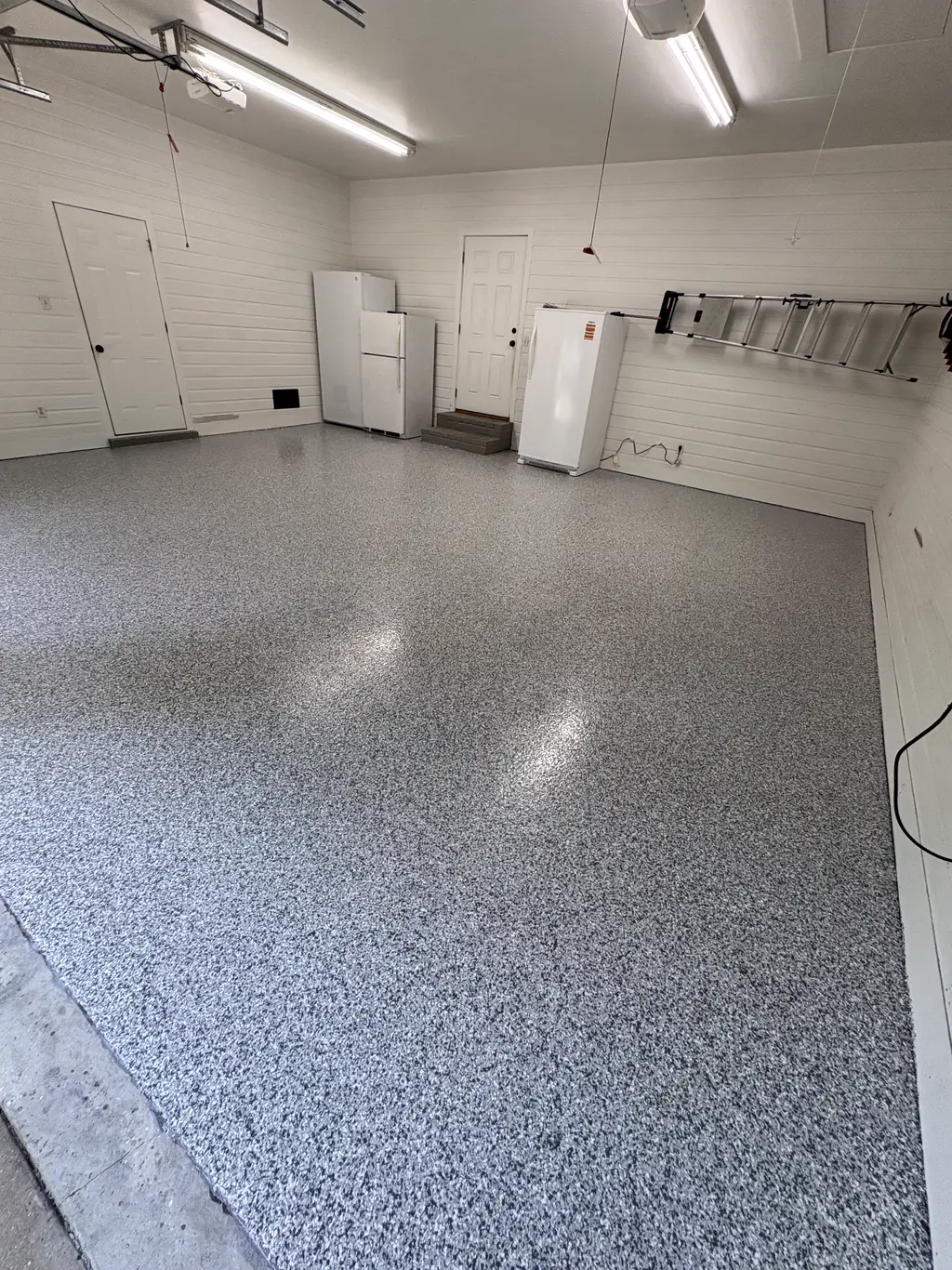 Workshop with a gray flake epoxy floor, white walls, and overhead shop lights