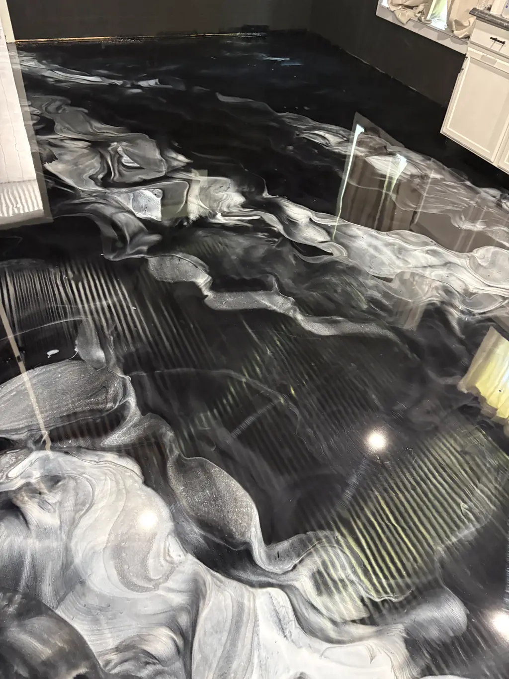 Black and white metallic epoxy floor with marble style veining in a kitchen