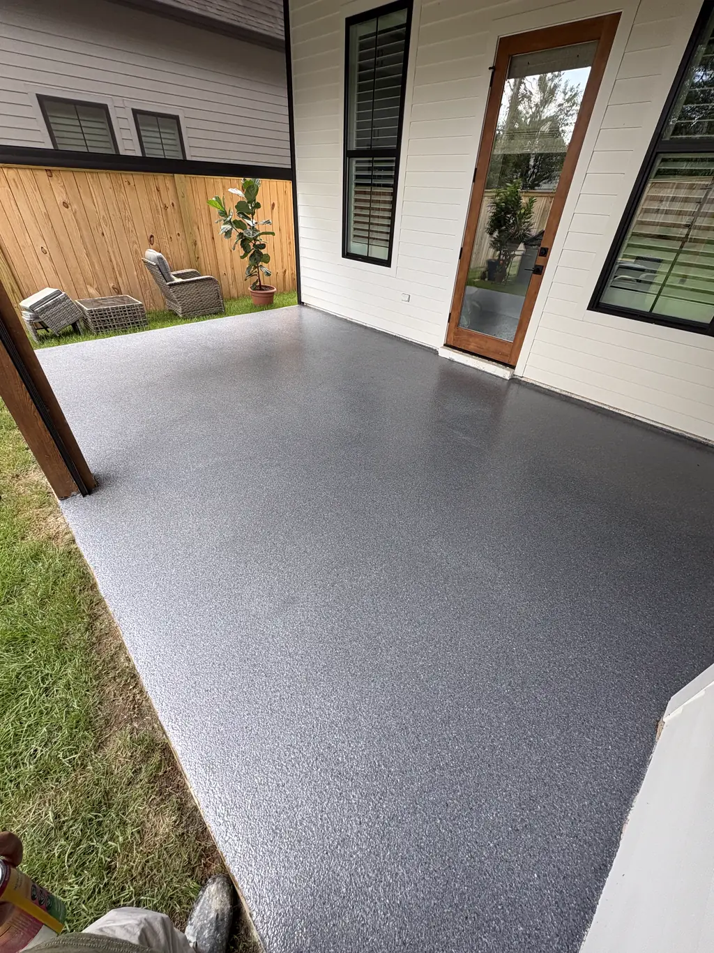 Covered back patio with a gray flake coating running up to the house