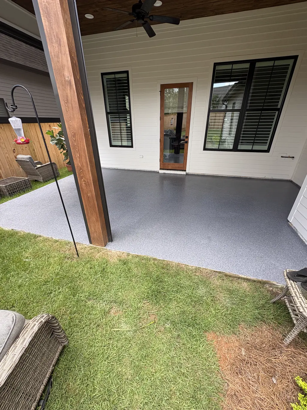 Covered back porch finished in gray flake coating with a view of the yard